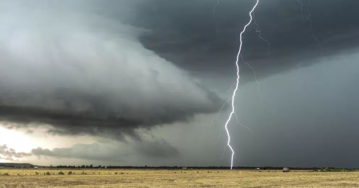 Cielo oscuro con nubes densas y un rayo sobre un campo en Sinaloa, México, durante el monzón.