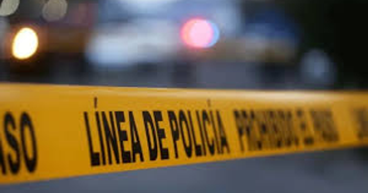 Cinta amarilla de policía con la frase 'LÍNEA DE POLICÍA' en un entorno nocturno desenfocado.