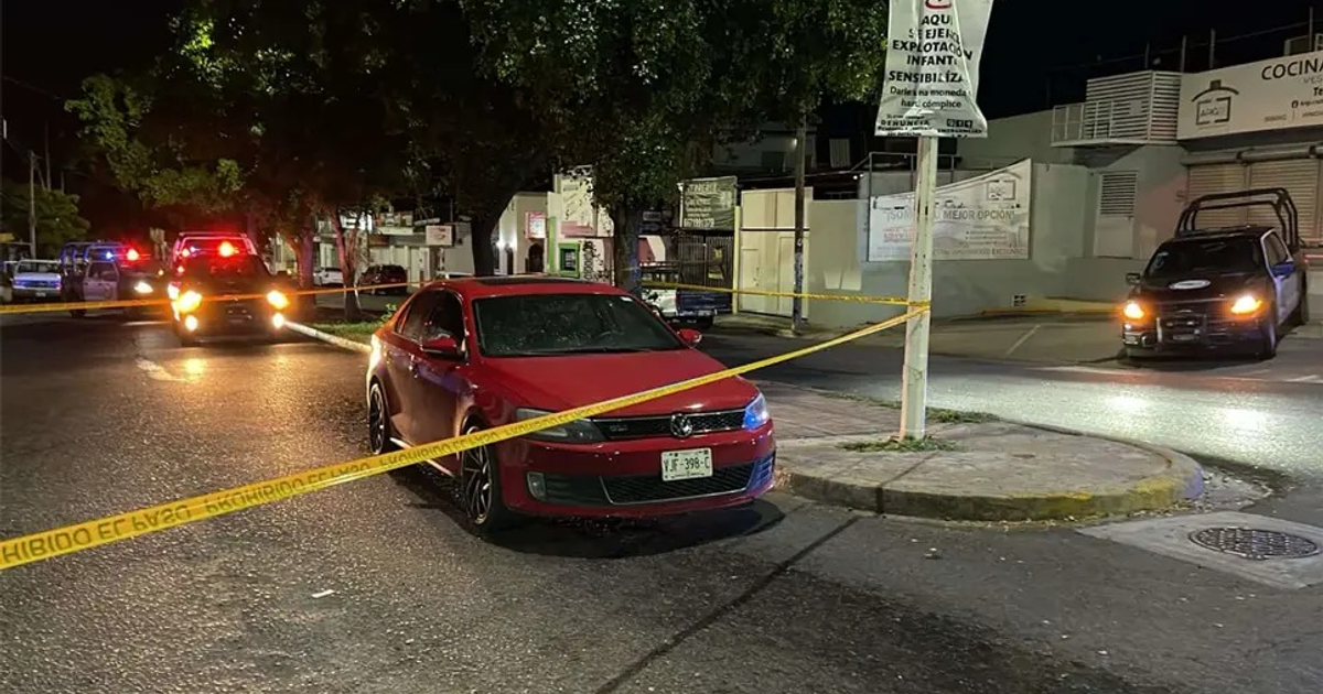 Calle nocturna en Culiacán con automóvil rojo y cinta de seguridad
