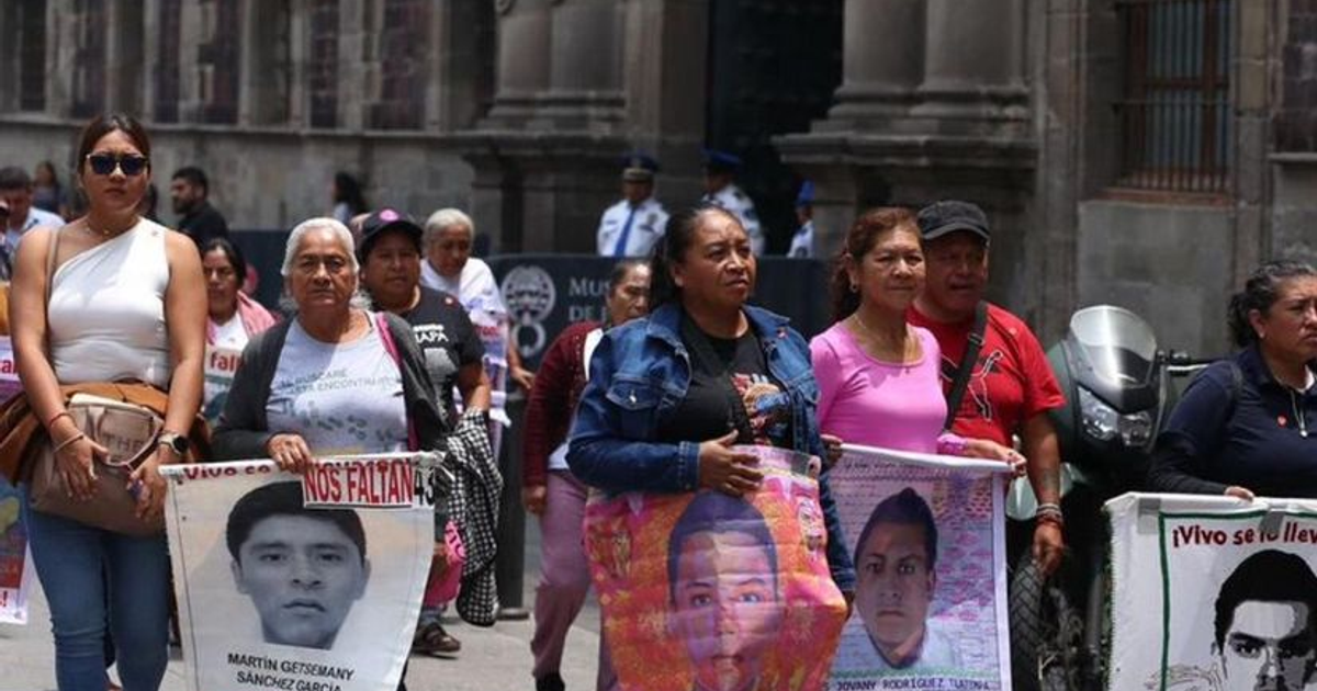 Manifestación por los 43 normalistas de Ayotzinapa con personas sosteniendo carteles de desaparecidos.