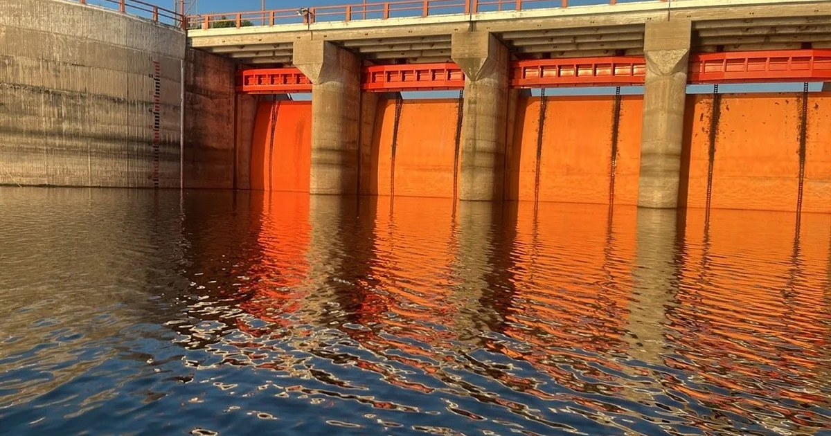 Estructura de concreto con pared naranja y agua reflejada, representando una presa en Sinaloa.