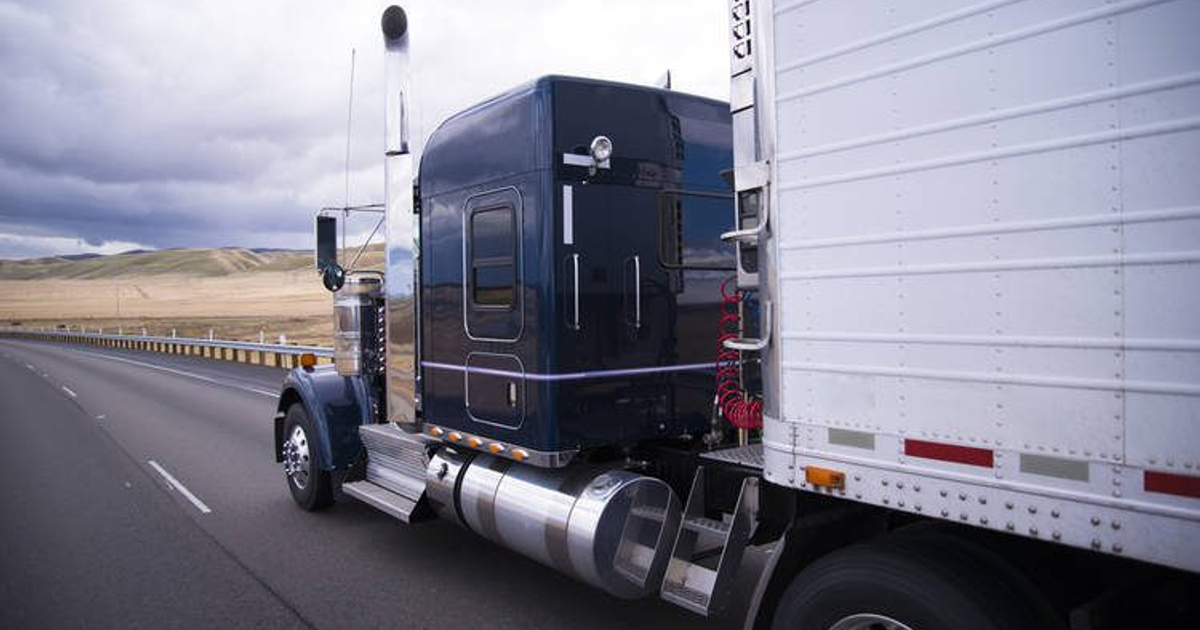 Camión de carga en carretera rural con montañas y cielo nublado