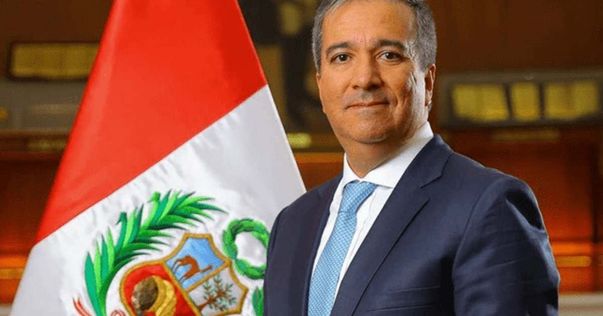 Raúl Pérez-Reyes, ministro peruano, en evento formal con bandera de Perú