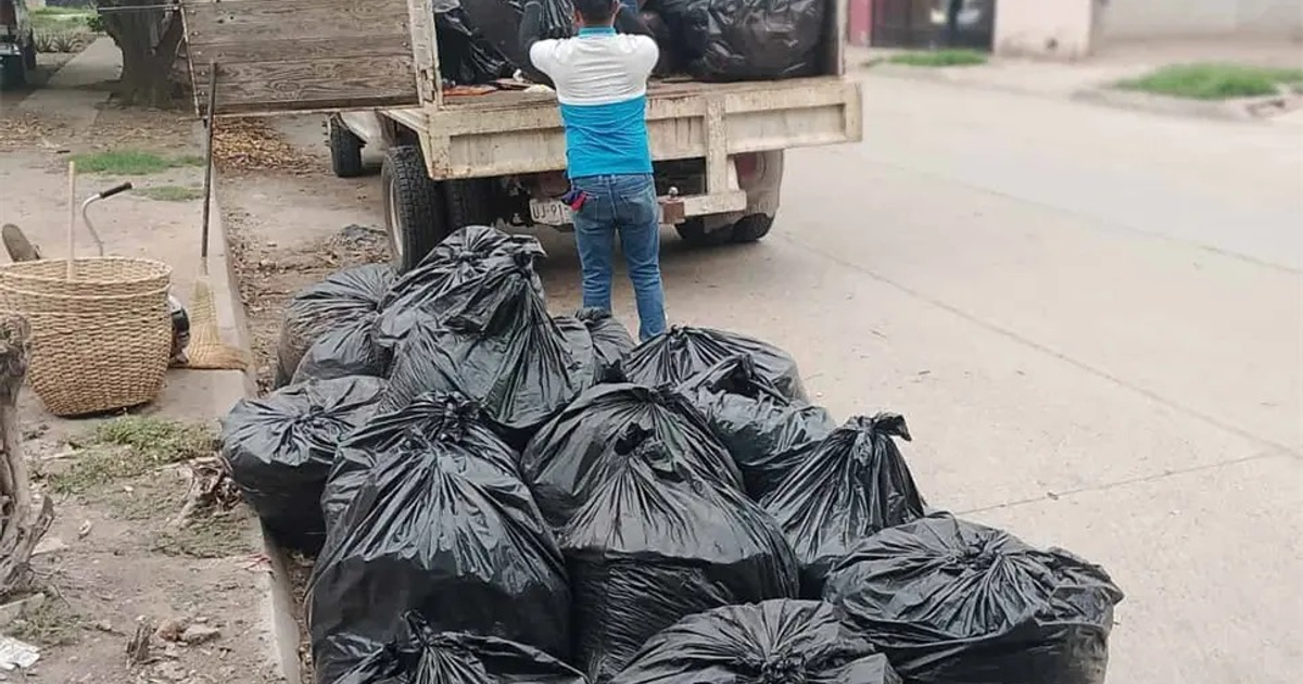 Sacos de basura apilados en una calle de Ahome, Sinaloa, con un trabajador cargando más en un camión.