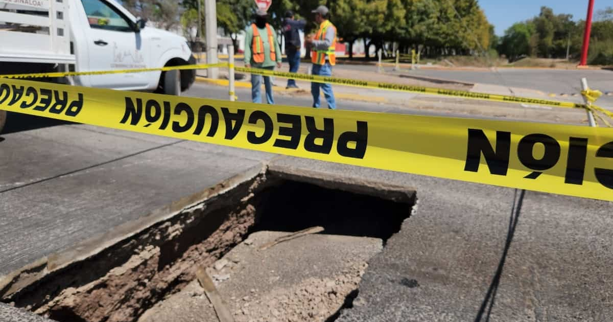 Socavón en Los Mochis con cinta de precaución y trabajadores cerca