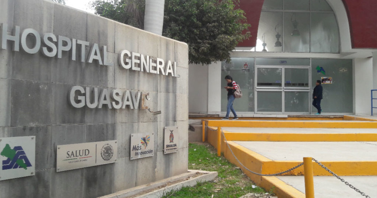 Entrada del Hospital General de Guasave con personas caminando hacia la entrada, letreros y símbolos de salud visibles.
