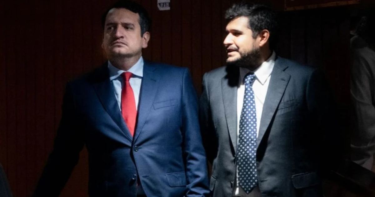 Dos hombres en trajes formales en un auditorio, uno con corbata roja y otro con corbata de puntos, relacionados con la suspensión de captura en Zacatecas.