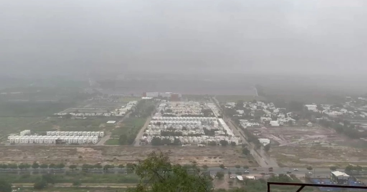 Vista de Culiacán con niebla y lluvia, edificios y áreas verdes apenas visibles.