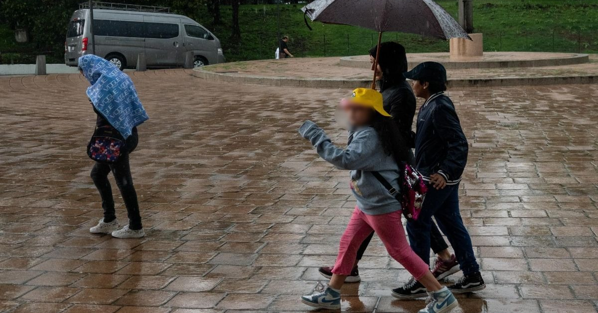 Personas caminando bajo la lluvia en Los Mochis, Sinaloa, tras suspensión de clases por lluvias.