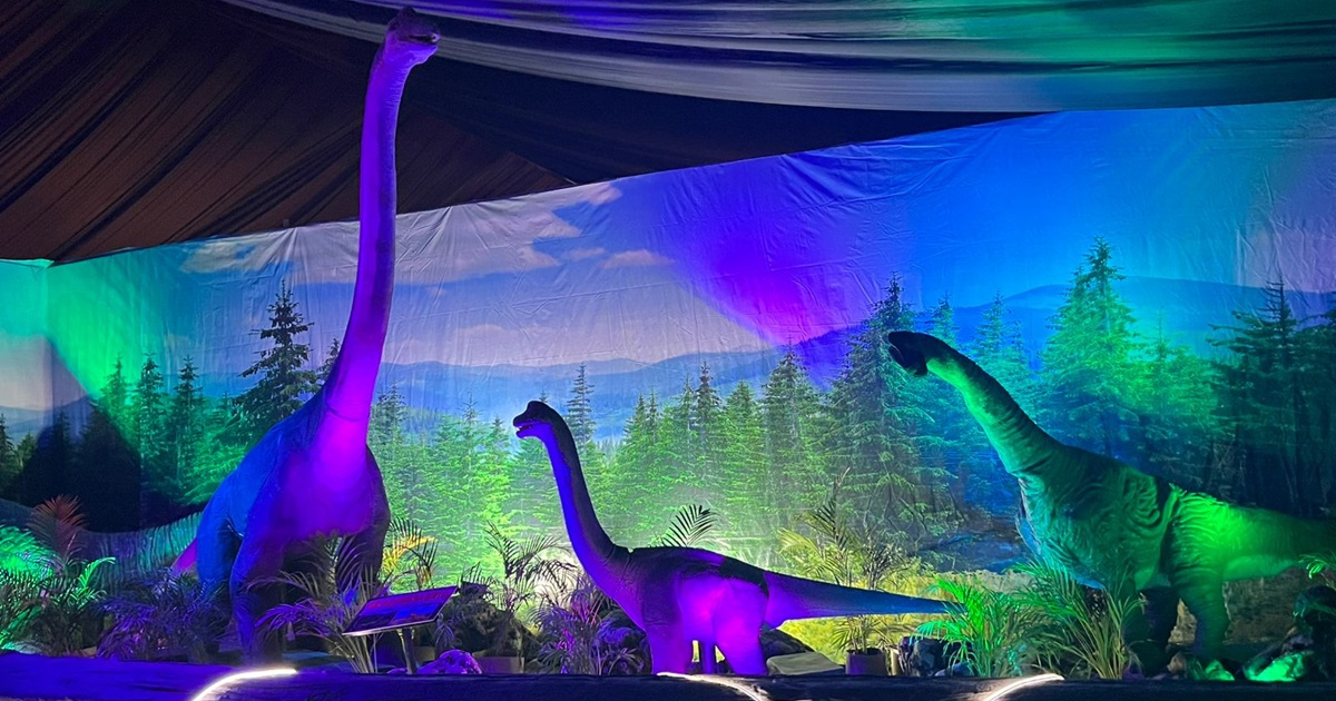 Exhibición de dinosaurios en Torám con un braquiosaurio y otros dinosaurios en un paisaje vibrante.