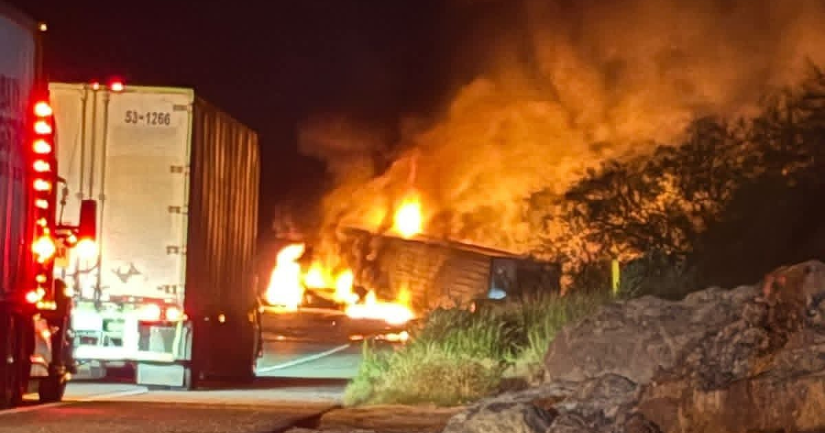 Tráiler en llamas en la carretera México 15 durante la noche, con humo y fuego visibles.