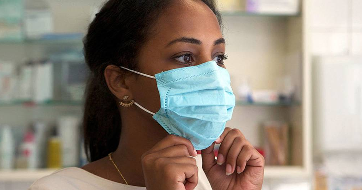 Persona con mascarilla azul en farmacia o clínica, relacionada con la variante XFG de COVID-19.