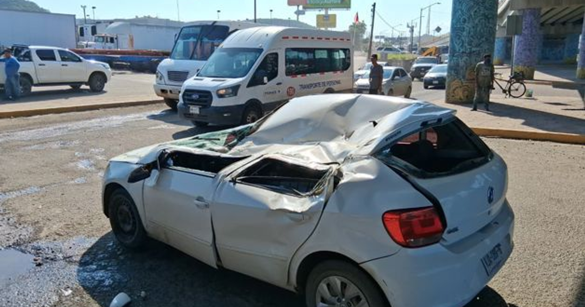 Automóvil blanco dañado tras accidente en Mazatlán con vehículo volcado encima