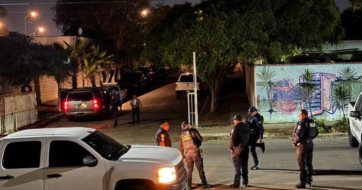 Calle nocturna en Tijuana con vehículos y policías tras ataque con explosivos