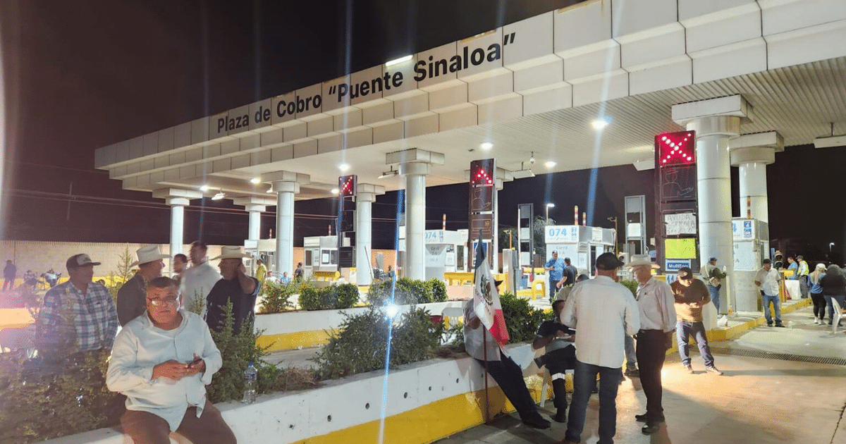 Vista nocturna de la plaza de cobro 'Puente Sinaloa' con personas y letreros luminosos.