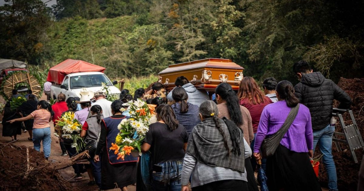 Cortejo fúnebre en Naupan, Puebla, con asistentes llevando un ataúd y flores, en un entorno natural.