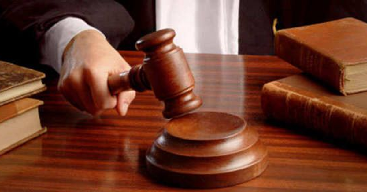 Martillo de juez levantado sobre una base con libros de leyes al lado, simbolizando justicia en un entorno legal.