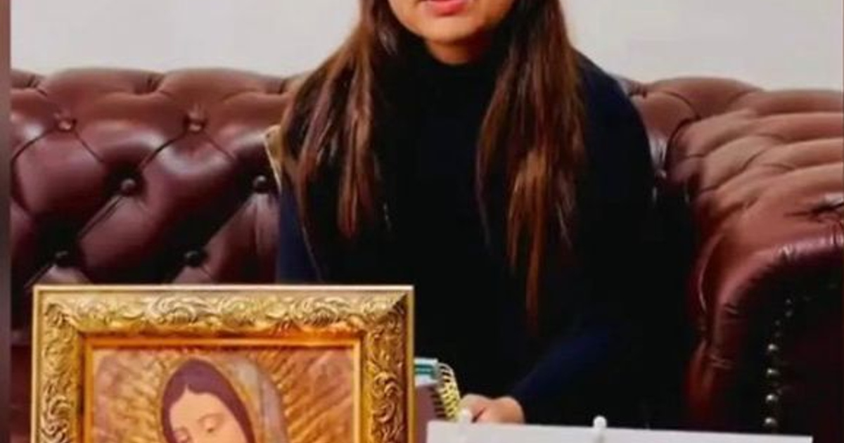 Persona sentada en sofá de cuero marrón con cuaderno y pintura religiosa en el fondo.