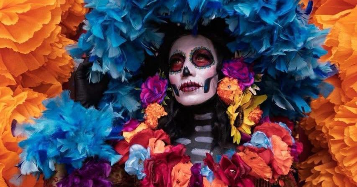 Persona con maquillaje de calavera y flores coloridas, representando el Día de Muertos en México.