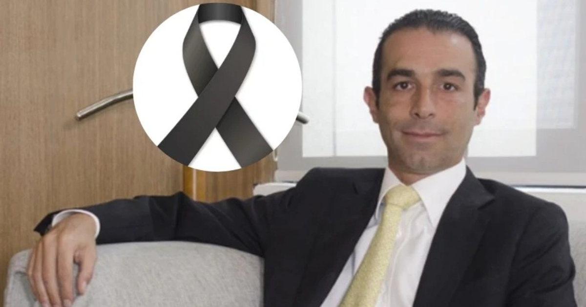 Hombre en traje oscuro con corbata amarilla y lazo negro de luto