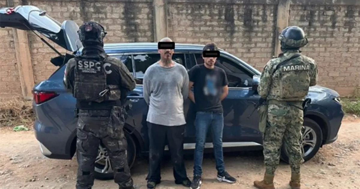 Dos hombres detenidos junto a un vehículo con el maletero abierto en Culiacán, rodeados por agentes de seguridad armados.