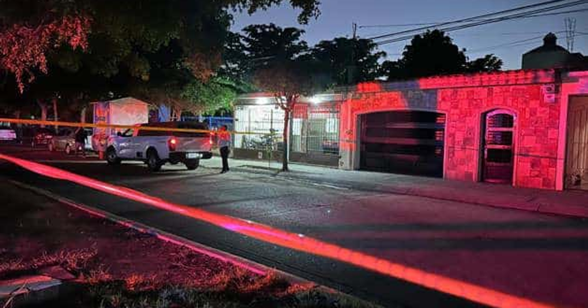 Calle nocturna en Los Mochis con luces de colores y cinta de restricción