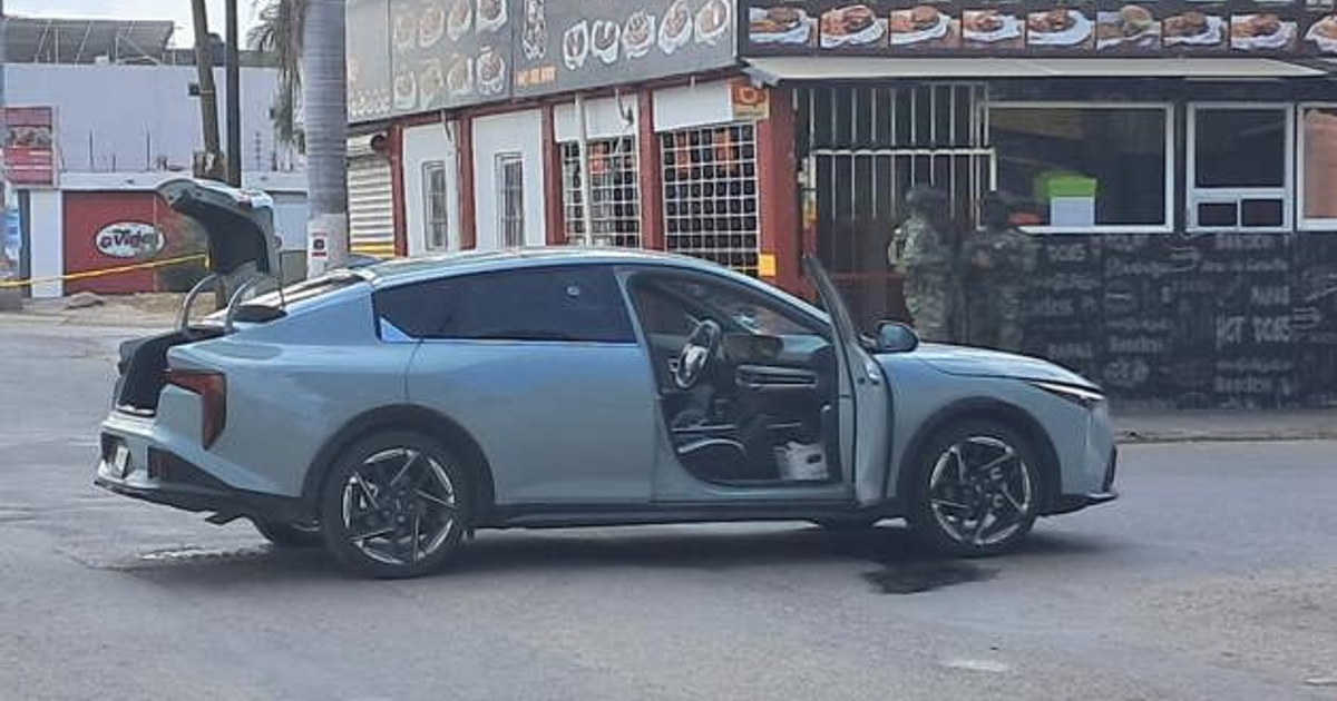 Automóvil azul claro en escena de enfrentamiento en Culiacán, Sinaloa, con puerta y maletero abiertos.