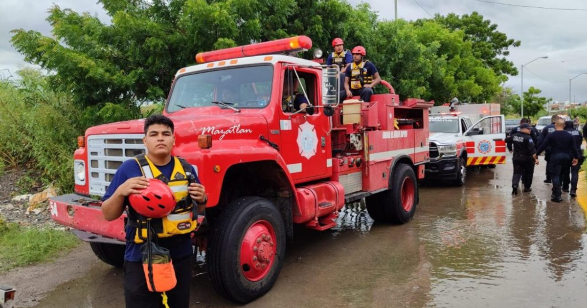 Bomberos en acción durante una emergencia en Mazatlán, Sinaloa, con un camión rojo y rescatistas en escena.