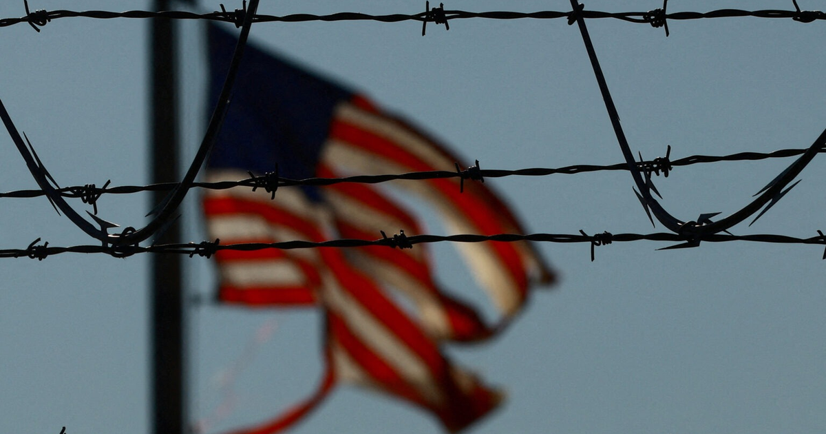 Bandera de Estados Unidos desenfocada con alambre de púas en primer plano