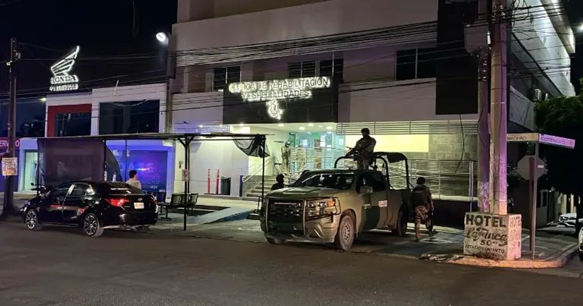 Entorno urbano nocturno en Culiacán con edificio iluminado y vehículos, relacionado con un ataque a balazos.