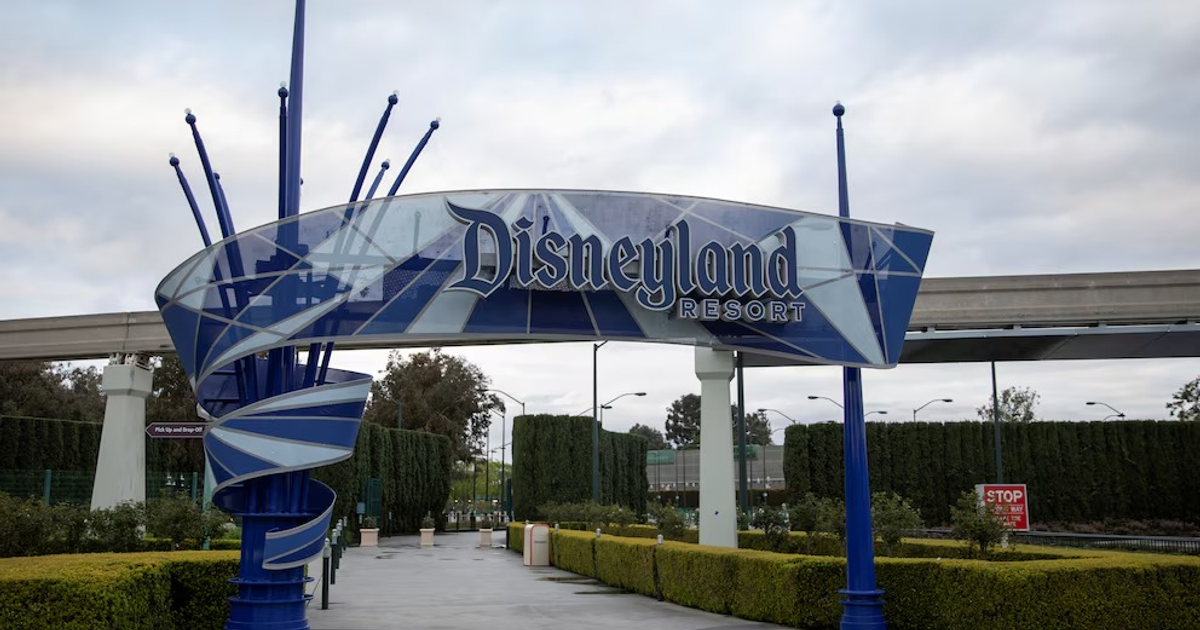 Entrada al Disneyland Resort con letrero azul y blanco, monorriel y cielo nublado