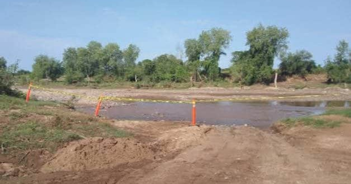Área al aire libre cerca de un arroyo con vallas amarillas y postes naranjas, relacionada con un hallazgo en Mocorito.