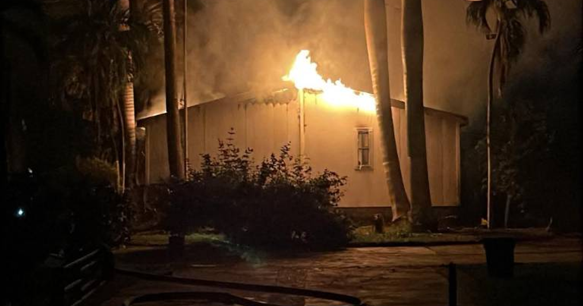 Edificio en llamas durante la noche en Culiacán, con humo y árboles cercanos.