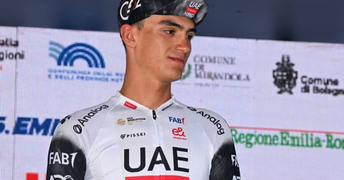 Ciclista del UAE Emirates en evento con fondo de pantallas y logotipos de patrocinadores