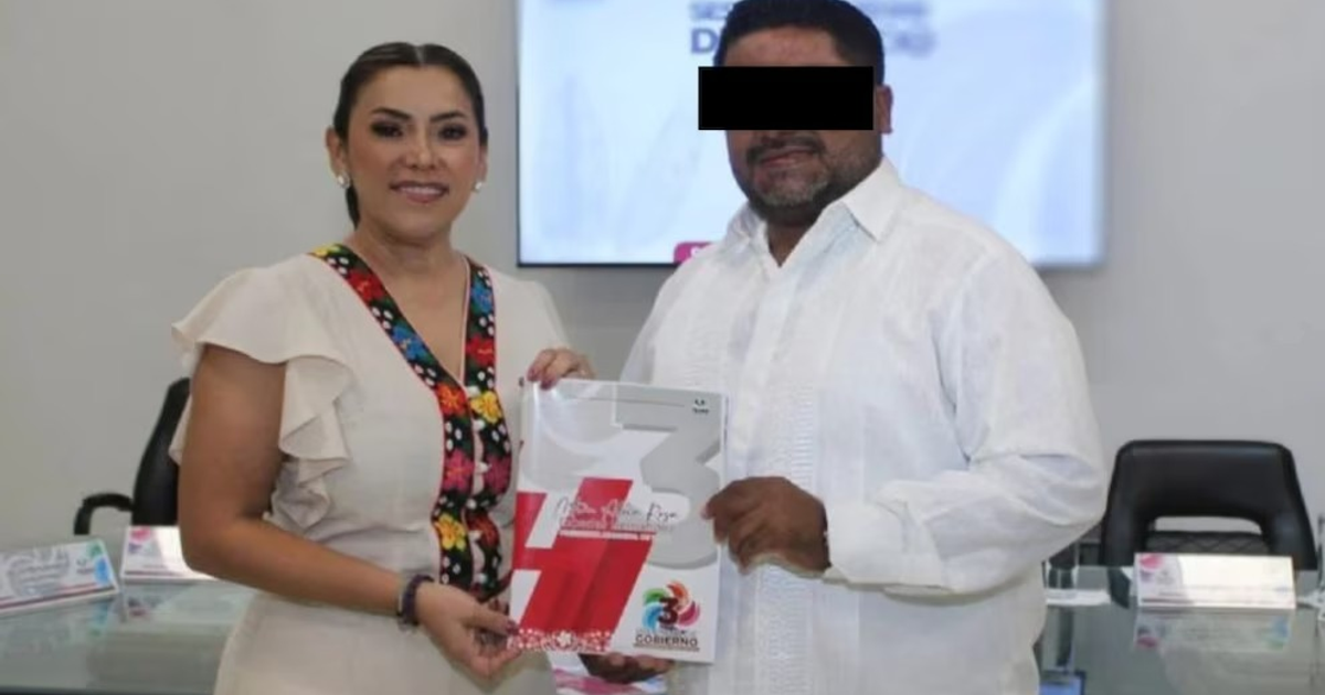 Dos personas en una oficina sosteniendo un documento, una con blusa clara y otra con camisa blanca.