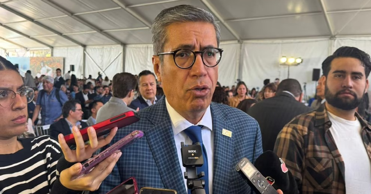 Hombre en conferencia de prensa rodeado de personas con teléfonos móviles, relacionado con investigación al exfiscal Jesús Figueroa Ortega.