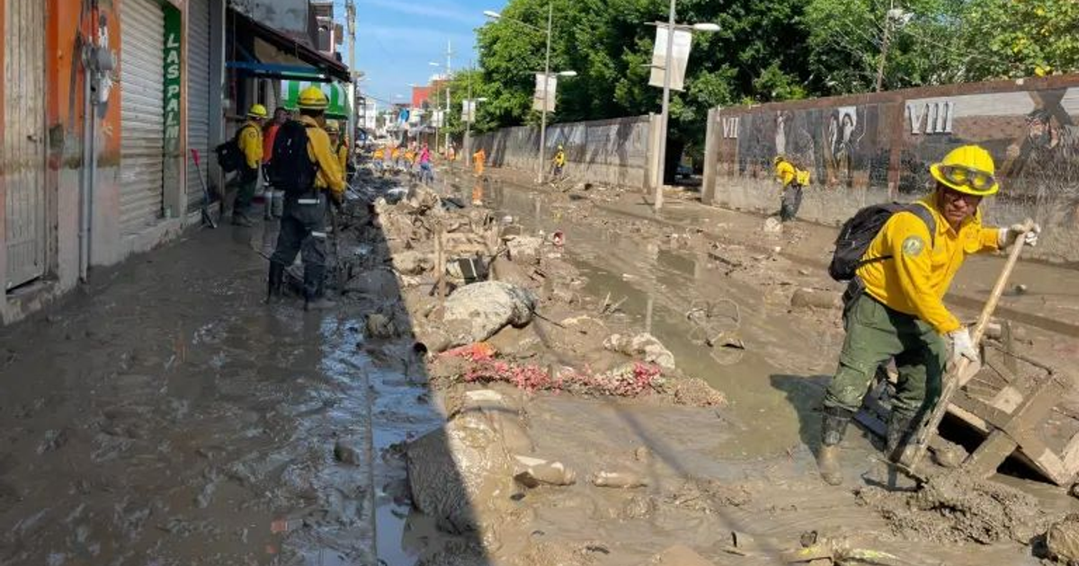 Trabajadores limpiando una calle llena de barro tras inundaciones en Veracruz