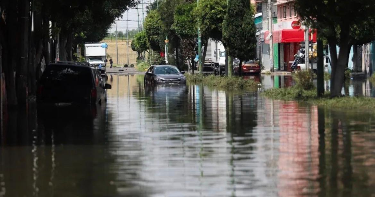 Calle inundada en México con vehículos sumergidos, reflejando el impacto de las lluvias torrenciales.