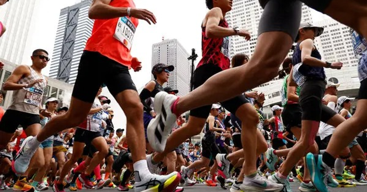 Grupo de corredores en maratón urbano en Mazatlán, Sinaloa, con edificios altos de fondo.