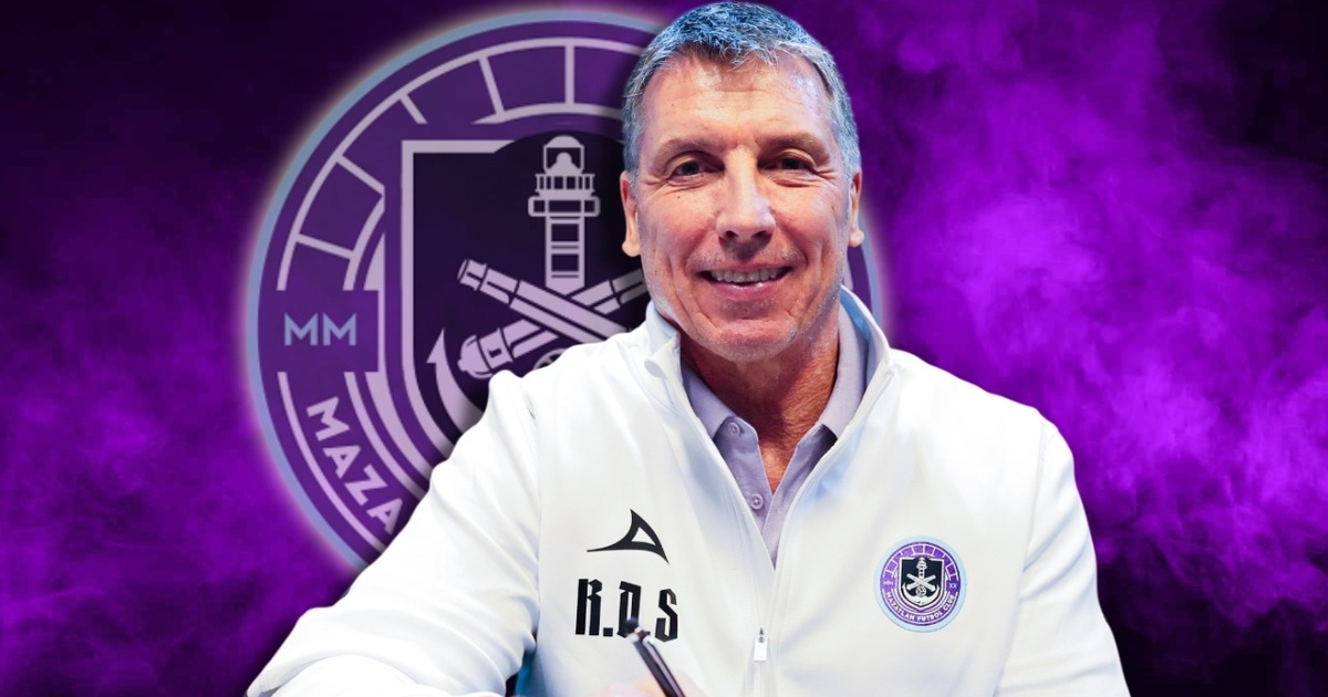Robert Dante Siboldi, entrenador de Mazatlán FC, sonríe con chaqueta blanca y fondo morado.