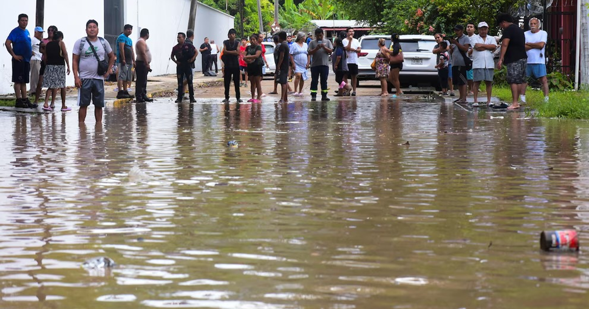 Personas en una calle inundada en Xalapa, Veracruz, tras el desbordamiento del río Cazones.