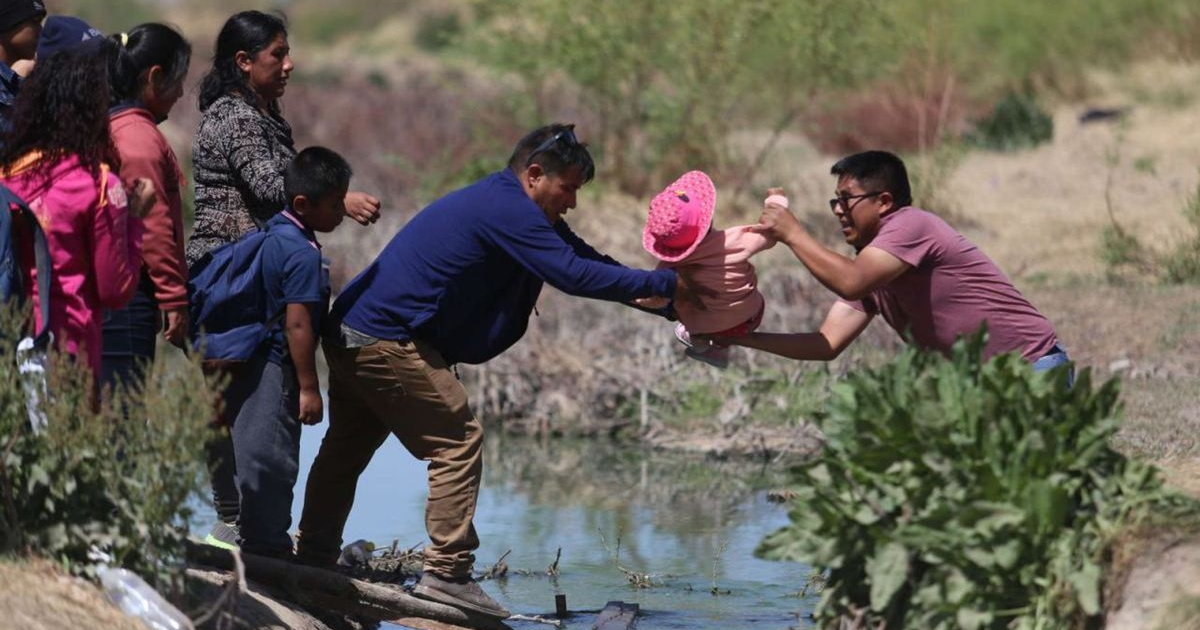 Personas en entorno natural ayudando a una niña cerca de un cuerpo de agua, simbolizando cooperación comunitaria.