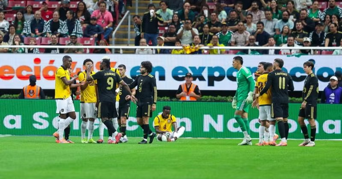 Jugadores de México y Ecuador discuten en el campo durante un partido en el Estadio Akron, con espectadores y un portero visibles en el fondo.