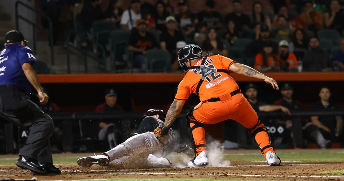 Receptor de los Naranjeros intenta tocar a un corredor de los Tomateros en un partido de béisbol.