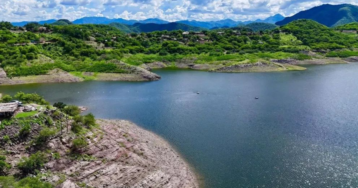 Vista panorámica de un embalse en Sinaloa rodeado de colinas y montañas, con un cielo parcialmente nublado y vegetación densa.