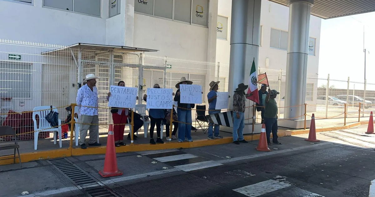Manifestantes agrícolas en caseta El Pisal, Culiacán, con pancartas y banderas.