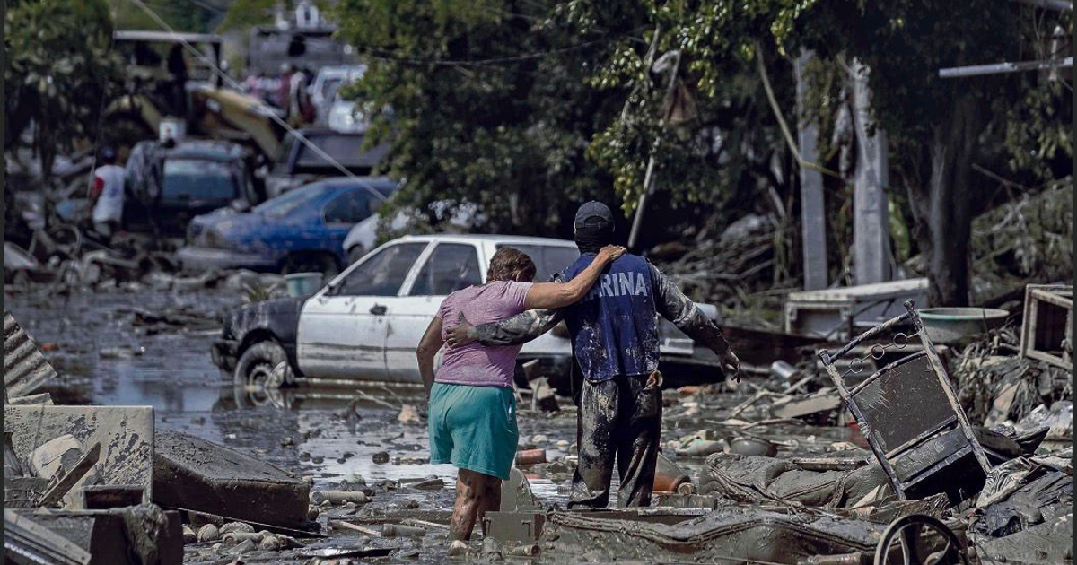 Dos personas caminan entre escombros e inundaciones tras el paso de la perturbación tropical 90-E en México.
