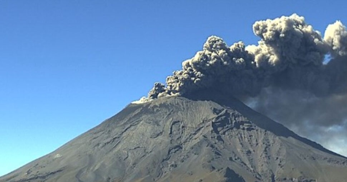 Erupción del volcán Popocatépetl con humo y ceniza en el aire, cielo despejado y laderas visibles.