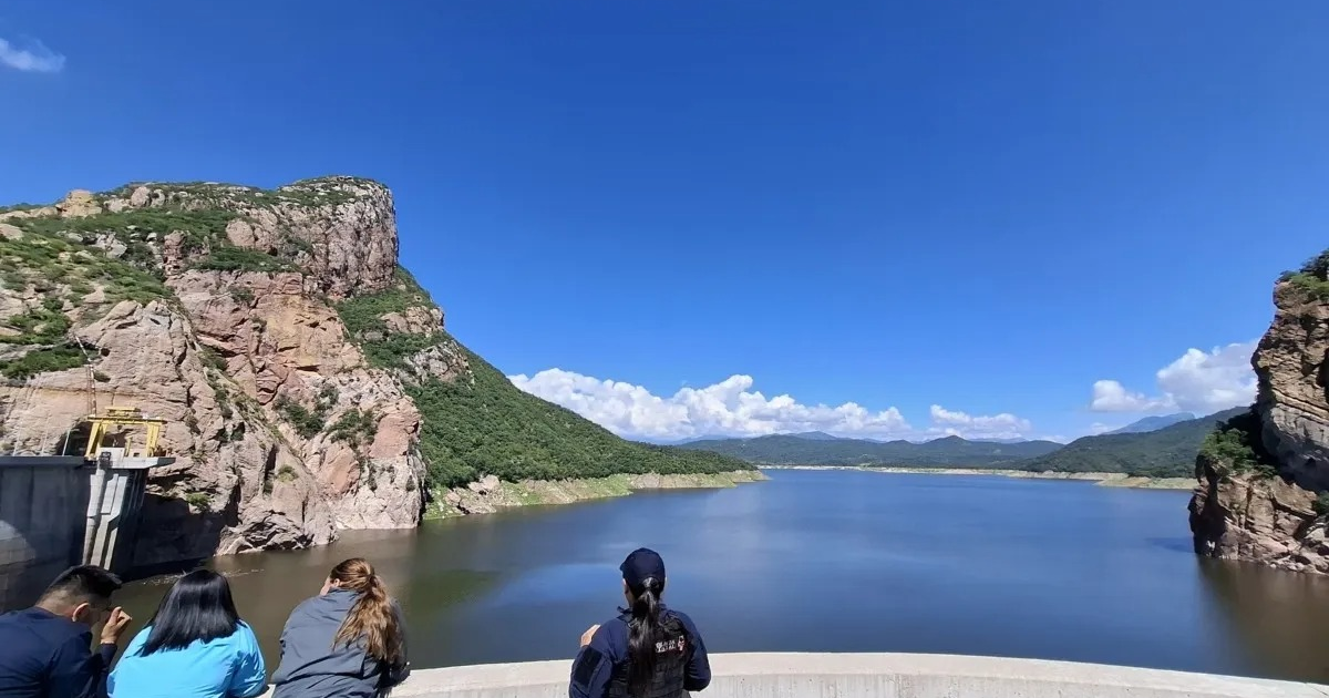 Vista de la Presa Luis Donaldo Colosio con montañas y personas observando el paisaje