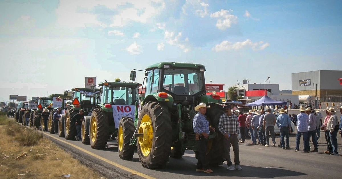 Tractores en protesta de productores de maíz en Sinaloa, con pancartas de desacuerdo y personas congregadas.